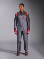Tuta Alpinestars KMX-9 V3 Graphic 6, tuta da kart, antracite, nero e rosso, motivo grafico grigio maculato, pannelli neri sull'interno di braccia e gambe, loghi Alpinestars rossi sulle spalle e sul petto, indossata con guanti da corsa rossi e scarpe nere