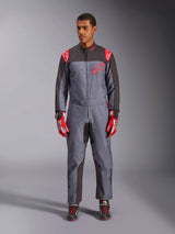 Tuta Alpinestars KMX-9 V3 Graphic 6, tuta da kart, antracite, nero e rosso, motivo grafico grigio maculato, pannelli neri sull'interno di braccia e gambe, loghi Alpinestars rossi sulle spalle e sul petto, indossata con guanti da corsa rossi e scarpe nere