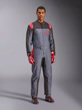 Tuta da karting Alpinestars KMX-9 V3 Graphic 6, grigio e antracite con dettagli rossi, caratterizzata da un'esclusiva grafica splash su petto e gambe, abbinata a guanti da corsa rossi e scarpe da karting nere, scatto a figura intera in studio.