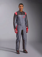 Tuta da karting Alpinestars KMX-9 V3 Graphic 6, grigio e antracite con dettagli rossi, caratterizzata da un'esclusiva grafica splash su petto e gambe, abbinata a guanti da corsa rossi e scarpe da karting nere, scatto a figura intera in studio.