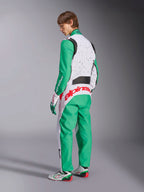 Tuta Alpinestars KMX-9 V3 Graphic 6, tuta da karting, bianco, verde e rosso, modello visto dal retro, con maniche e pannelli inferiori verdi, parte superiore del busto bianca con dettagli a macchioline nere, vistoso marchio Alpinestars rosso sulla parte bassa della schiena, abbinata a scarpe da karting bianche e verdi coordinate.