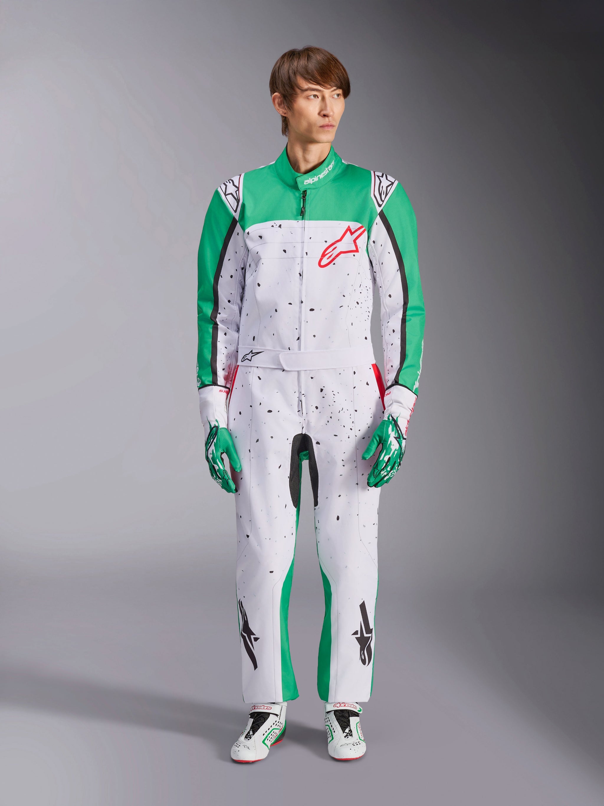 Tuta Alpinestars KMX-9 V3 Graphic 6, bianco, verde e rosso, tuta da karting intera con motivo grafico splatter nero, pannelli verdi su maniche e gambe, logo Alpinestars rosso sul petto, indossata con guanti e scarpe da corsa abbinati