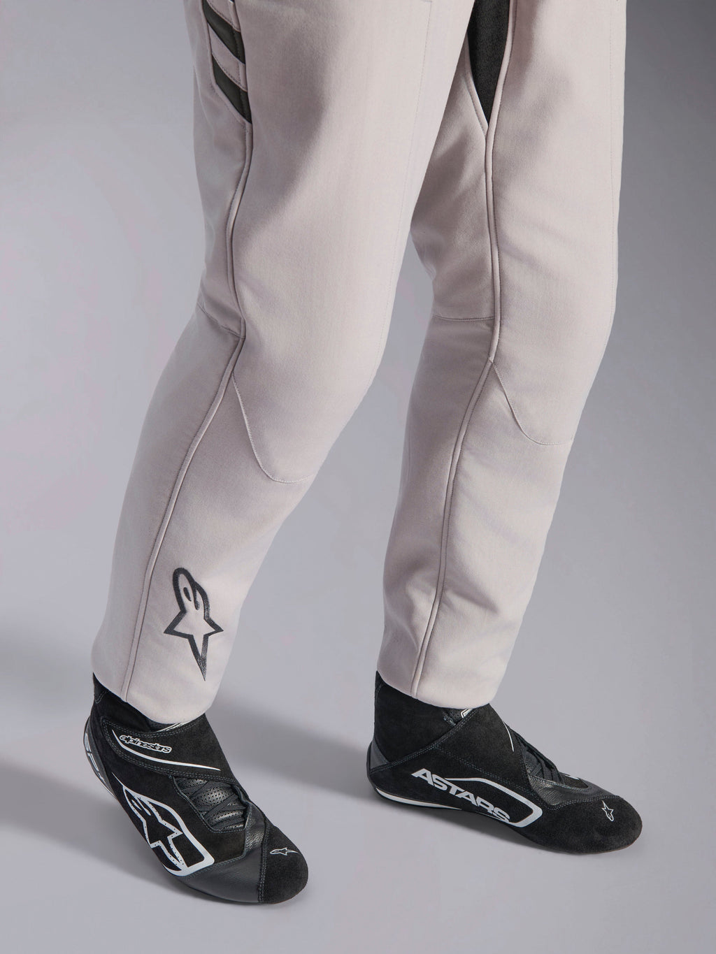Alpinestars GP Race V3 Suit FIA, tuta da corsa Silver Anthracite, dettaglio della parte inferiore delle gambe e stivaletti da corsa neri, con logo Astars nero sul polpaccio, abbigliamento professionale da motorsport con polsini a coste