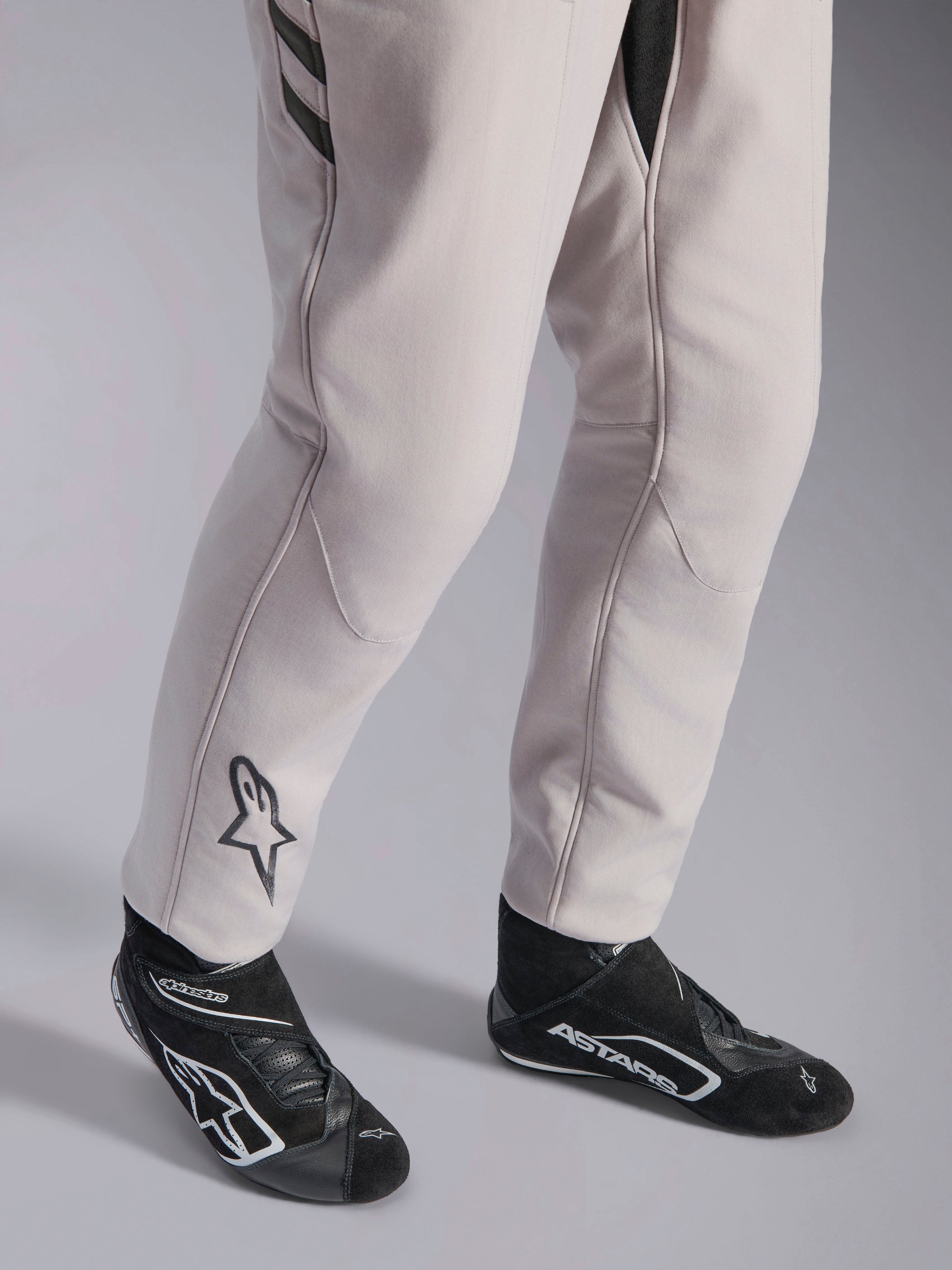 Alpinestars GP Race V3 Suit FIA, tuta da corsa Silver Anthracite, dettaglio della parte inferiore delle gambe e stivaletti da corsa neri, con logo Astars nero sul polpaccio, abbigliamento professionale da motorsport con polsini a coste