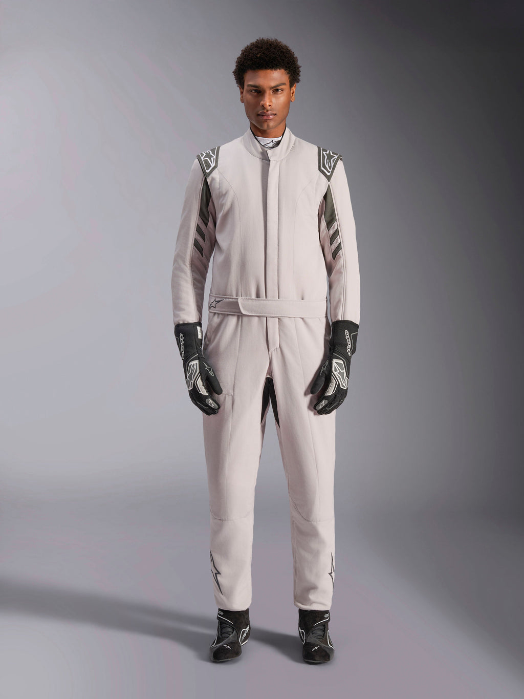 Alpinestars GP Race V3 Suit FIA in Silver Anthracite, tuta da auto monopezzo indossata da un modello, con spalline e dettagli grigio scuro, abbinata a guanti e stivaletti da corsa neri, abbigliamento protettivo professionale per motorsport.