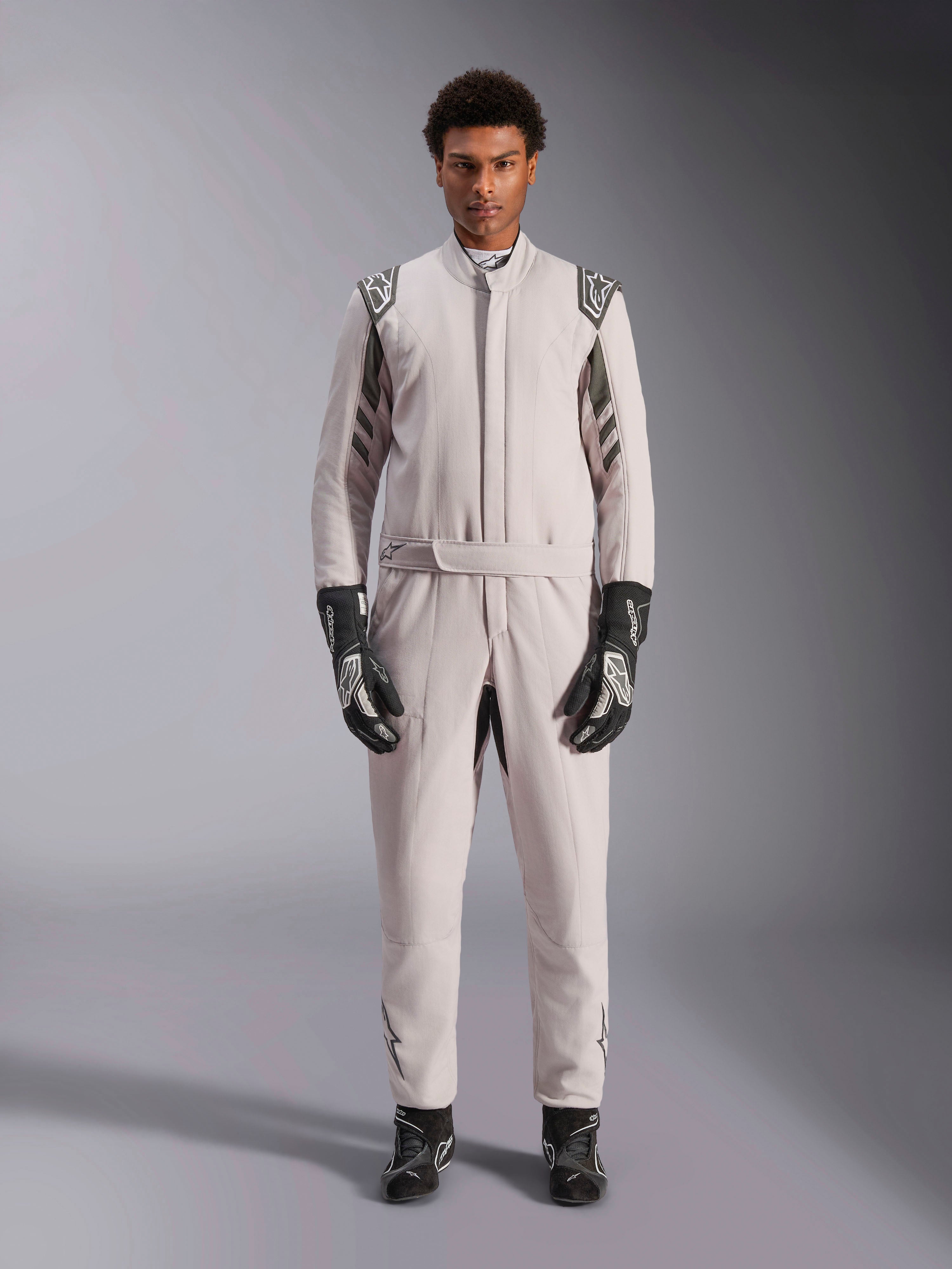 Alpinestars GP Race V3 Suit FIA in Silver Anthracite, tuta da auto monopezzo indossata da un modello, con spalline e dettagli grigio scuro, abbinata a guanti e stivaletti da corsa neri, abbigliamento protettivo professionale per motorsport.