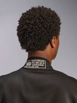 Alpinestars Tuta GP Race V3 FIA, tuta da corsa nera, primo piano dello scollo posteriore con patch di certificazione FIA 8856-2018, vista dettagliata dell'omologazione di sicurezza e logo Alpinestars, abbigliamento per motorsport ad alte prestazioni