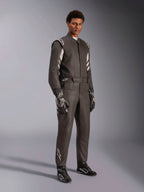 Pilota con tuta Alpinestars GP Race V3 FIA, tuta da corsa automobilistica nera e argento, completa di guanti e scarpe coordinati, con accenti argento sulle spalle e sulla parte inferiore della gamba, abbigliamento professionale da competizione con vestibilità su misura.