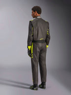 Vista posteriore della tuta Alpinestars GP Race V3 FIA, nera con accenti giallo fluo, indossata con guanti e stivali da corsa abbinati, equipaggiamento professionale per gare automobilistiche con costruzione aramidica a due strati
