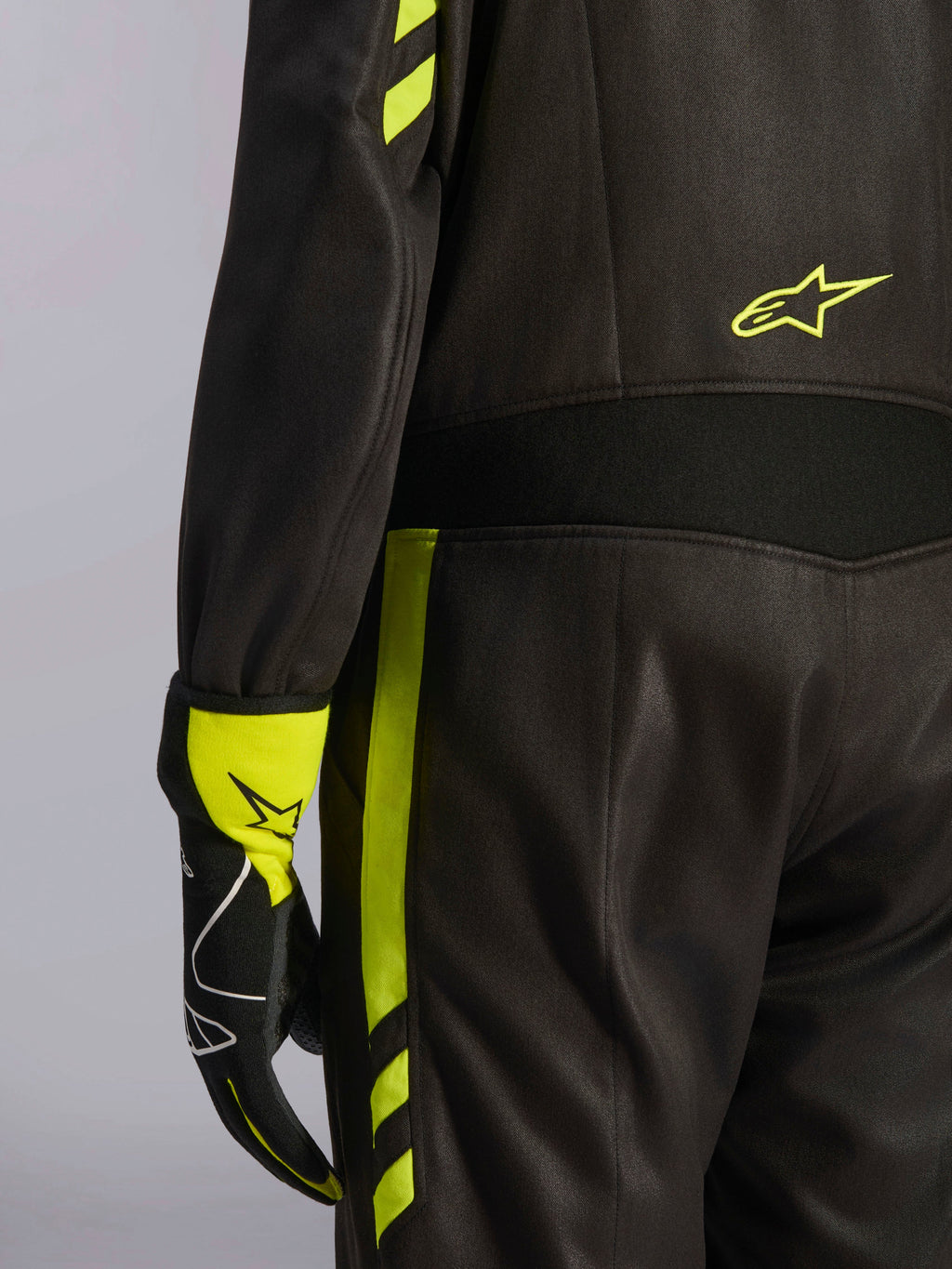 Alpinestars GP Race V3 Suit FIA, nero e giallo fluo, dettaglio ravvicinato della vita e del lato gamba, con pannelli elasticizzati in aramide e guanto da corsa coordinato, abbigliamento professionale per corse automobilistiche