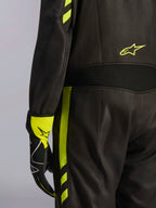 Alpinestars GP Race V3 Suit FIA, nero e giallo fluo, dettaglio ravvicinato della vita e del lato gamba, con pannelli elasticizzati in aramide e guanto da corsa coordinato, abbigliamento professionale per corse automobilistiche