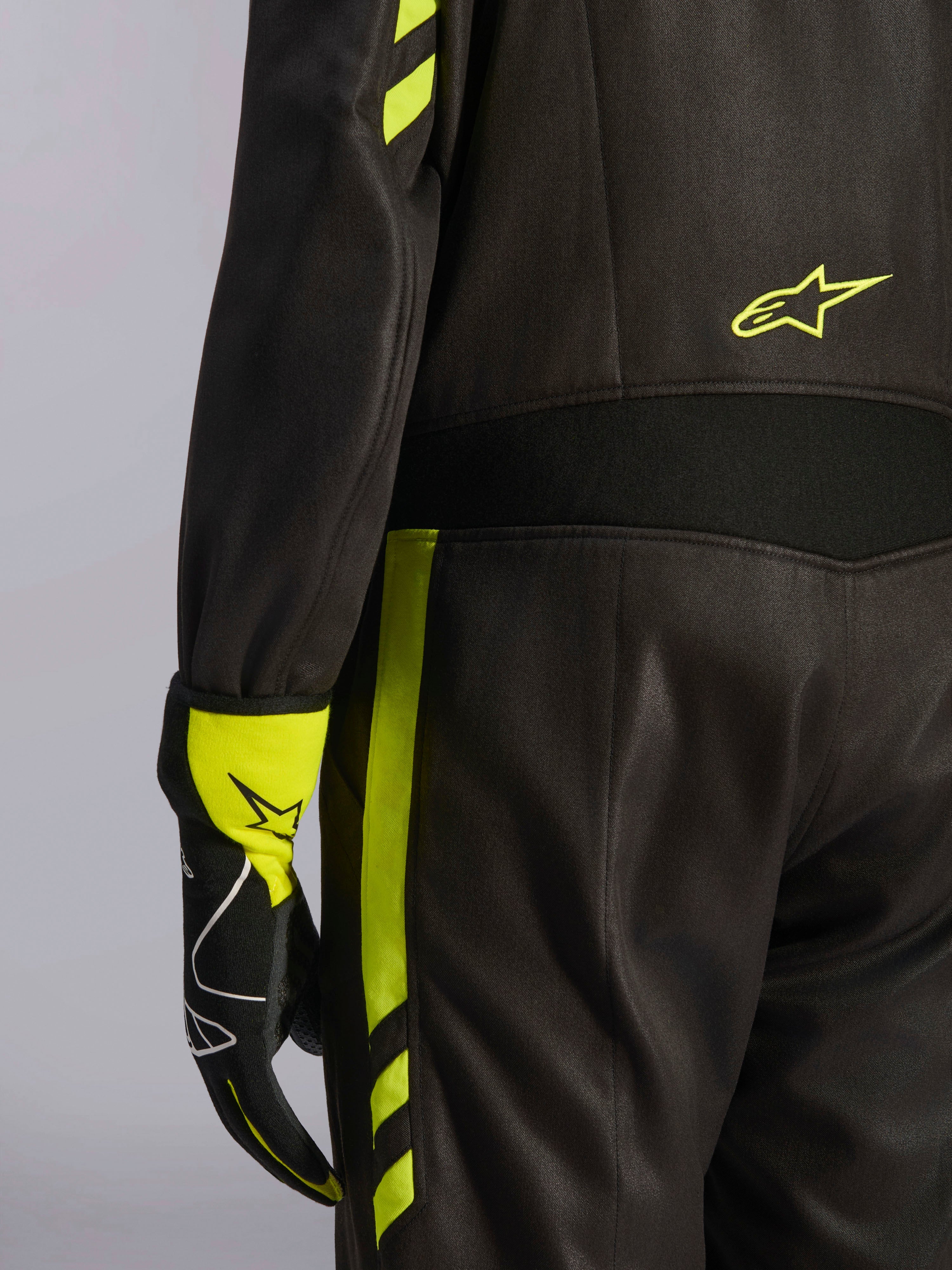 Alpinestars GP Race V3 Suit FIA, nero e giallo fluo, dettaglio ravvicinato della vita e del lato gamba, con pannelli elasticizzati in aramide e guanto da corsa coordinato, abbigliamento professionale per corse automobilistiche