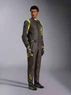 Alpinestars GP Race V3 Suit FIA, tuta da corsa auto, nero e giallo fluo, indossata da un modello con guanti e stivali da corsa abbinati, con vivaci accenti gialli sulle spalle e sulle gambe, attrezzatura professionale per motorsport