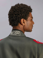 Alpinestars GP Race V3 Suit FIA, tuta da corsa Antracite Rosso, primo piano del colletto posteriore che mostra l'etichetta di certificazione FIA 8856-2018 e le spalline rosse, vista dettagliata di abbigliamento professionale per motorsport.