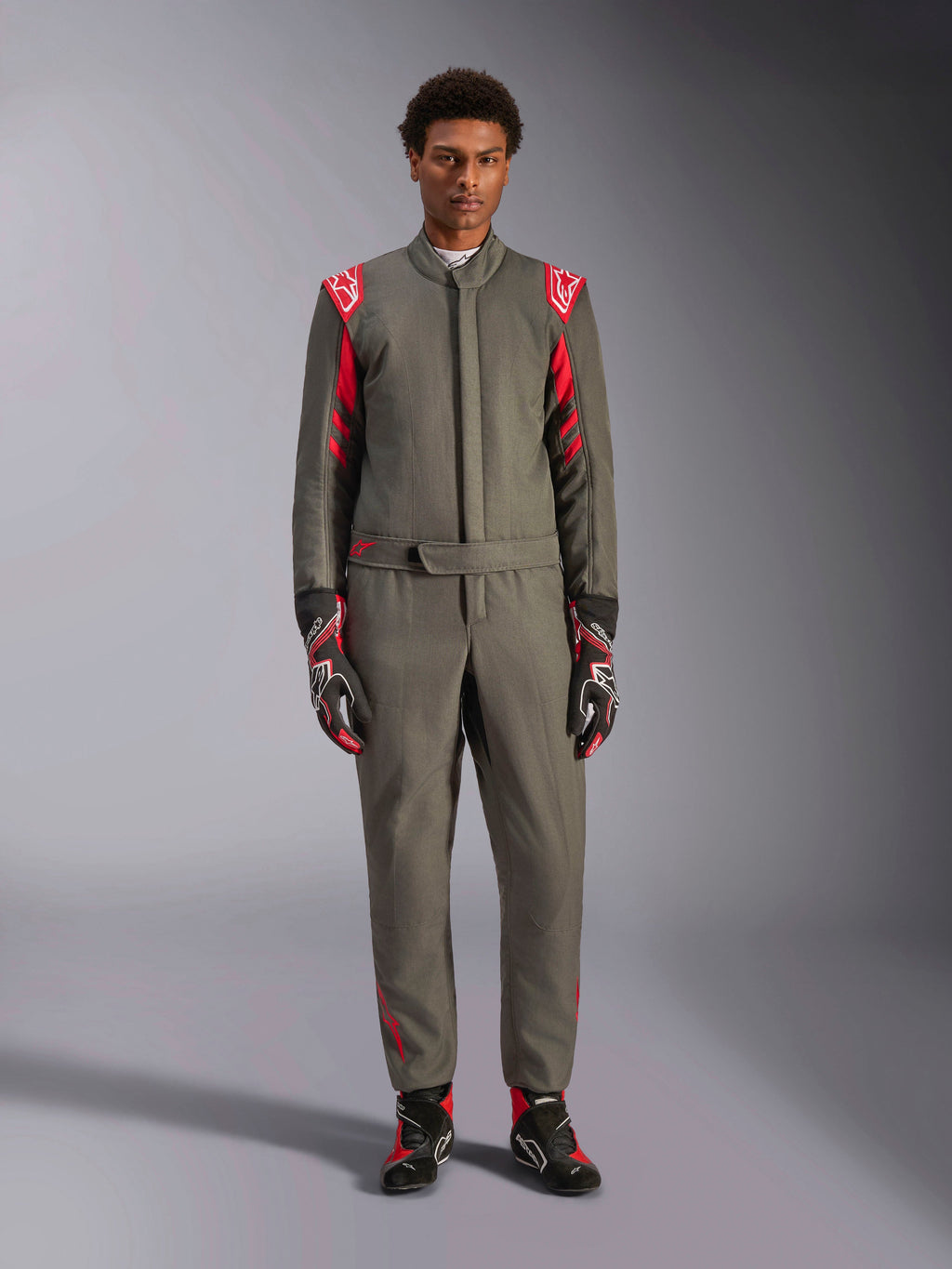 Alpinestars GP Race V3 Suit FIA, tuta da auto, antracite e rosso, indossata da un modello con guanti e stivali coordinati, con spalline rosse e loghi, abbigliamento professionale da motorsport per guida sportiva