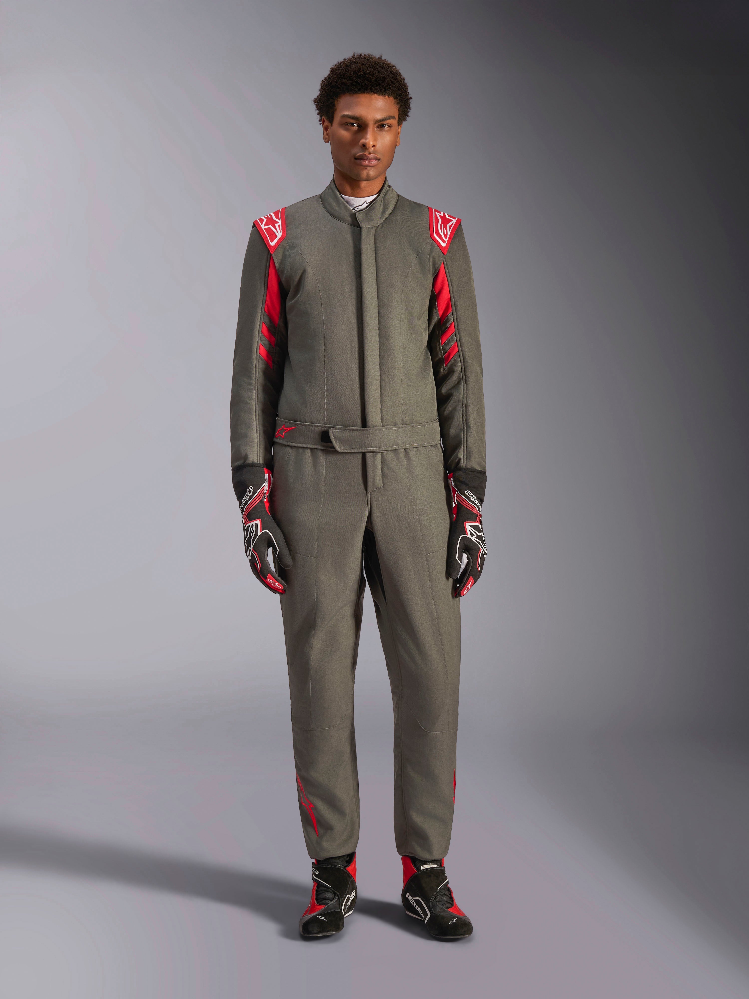 Alpinestars GP Race V3 Suit FIA, tuta da auto, antracite e rosso, indossata da un modello con guanti e stivali coordinati, con spalline rosse e loghi, abbigliamento professionale da motorsport per guida sportiva