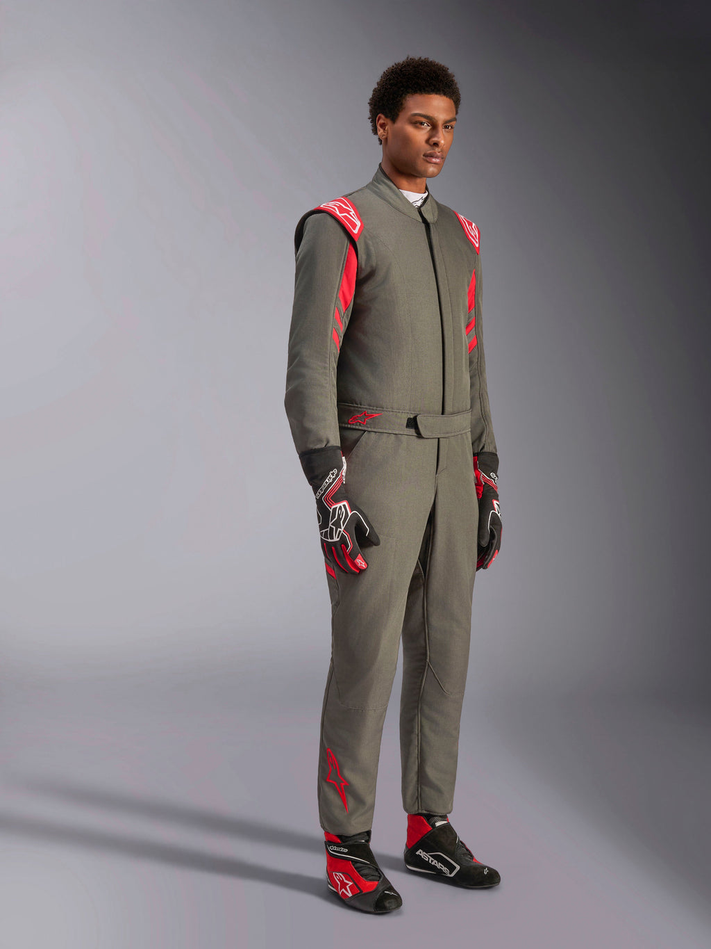 Alpinestars GP Race V3 Suit FIA, tuta da corsa auto antracite e rosso, indossata con guanti e scarpe da corsa abbinati, con spalline e loghi rossi, elegante design tecnico a due strati per il motorsport