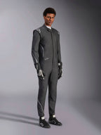 Tuta Alpinestars Hypertech V3, tuta da auto racing, nero e Dark Shadow, indossata da un modello con guanti neri e scarpe da corsa coordinati, vestibilità slim atletica, loghi Alpinestars e accenti grigio chiaro, abbigliamento protettivo professionale per motorsport