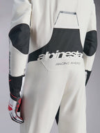 Tuta Alpinestars Hypertech V3, tuta da auto racing bianca, nera e argento, vista posteriore con grande logo 'alpinestars' nero e testo 'RACING AHEAD', con pannelli elasticizzati neri su gomiti e zona lombare, abbigliamento protettivo professionale da motorsport.