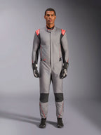 Alpinestars Hypertech V3 Suit, tuta da corsa professionale in grigio medio, nero e rosso fluo, indossata da un modello con guanti e scarpe da corsa neri, caratterizzata da una vestibilità atletica, accenti rosso fluo sulle spalle e pannelli neri su ginocchia e fianchi.
