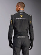 Vista posteriore della tuta Alpinestars Limited Edition Lamborghini GP Tech V4, nero con accenti oro, con scudetto Automobili Lamborghini e testo 'SQUADRA CORSE' sul retro, tuta da corsa professionale certificata FIA per competizioni automobilistiche