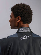 Alpinestars tuta GP Pro Comp V2 FIA, tuta da auto da uomo, nera e asfalto, dettaglio del colletto posteriore con certificazione FIA 8856-2018 e logo Astar bianco.