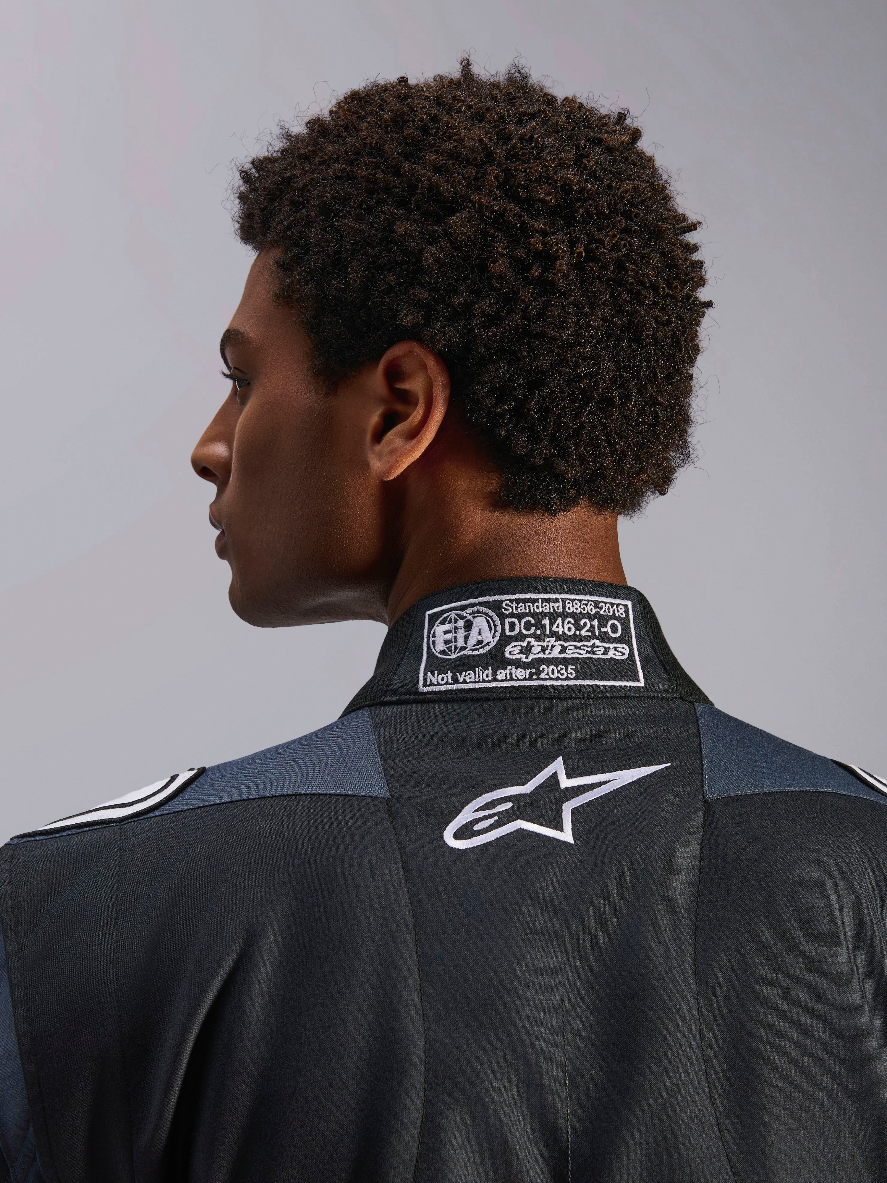 Alpinestars tuta GP Pro Comp V2 FIA, tuta da auto da uomo, nera e asfalto, dettaglio del colletto posteriore con certificazione FIA 8856-2018 e logo Astar bianco.