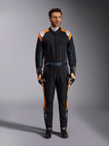 Alpinestars GP Pro Comp V2 FIA Suit, tuta da auto racing nero asfalto e arancione fluo, modello uomo che indossa equipaggiamento protettivo completo con guanti e scarpe da corsa abbinati, caratterizzata da loghi Alpinestars bianchi e vivaci pannelli laterali arancioni, abbigliamento professionale per motorsport