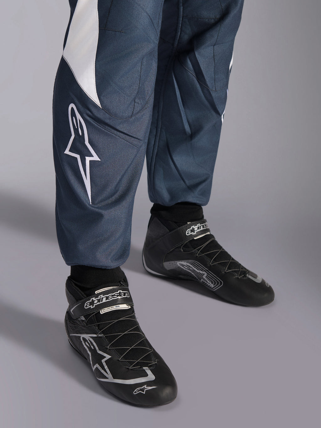 Alpinestars Tuta GP Pro Comp V2 FIA, tuta da corsa per auto, asfalto e ciano, dettaglio del logo e scarpe da corsa nere