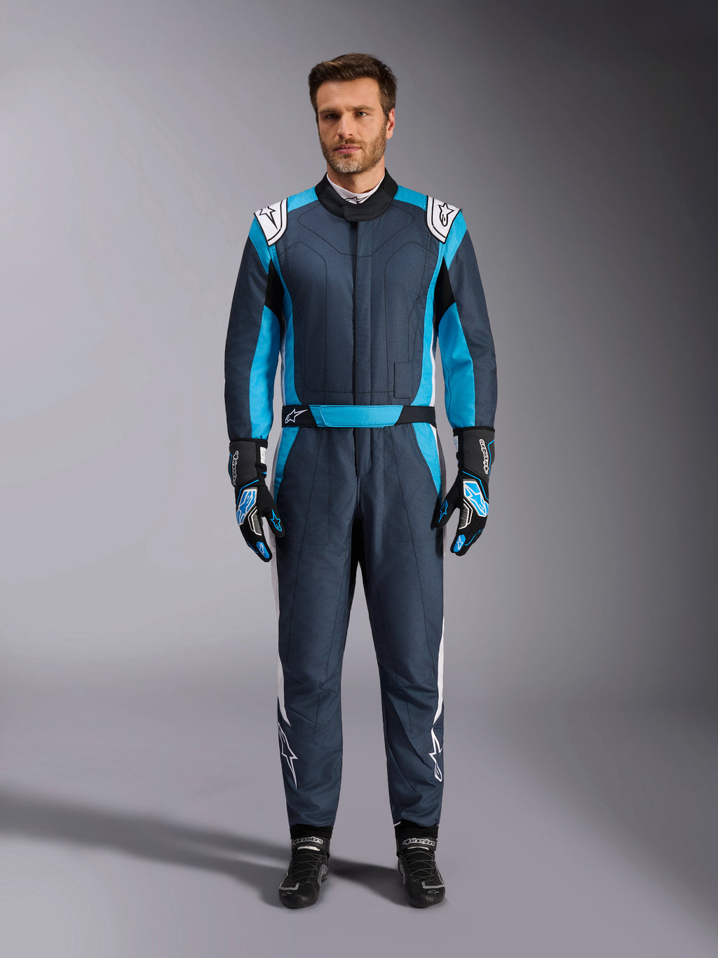 Alpinestars Tuta GP Pro Comp V2, tuta da corsa auto da uomo, grigio asfalto e blu ciano con accenti bianchi, certificata FIA, indossata con guanti e scarpe da gara coordinati