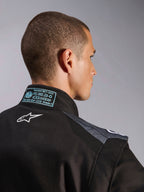 Tuta Alpinestars KMX-5 V3 in Nero e Dark Shadow, vista ravvicinata del retro e del colletto con logo Astars bianco, etichetta di certificazione FIA 8877-2022 Grado 1 e pannelli in mesh ventilato sulle spalle.