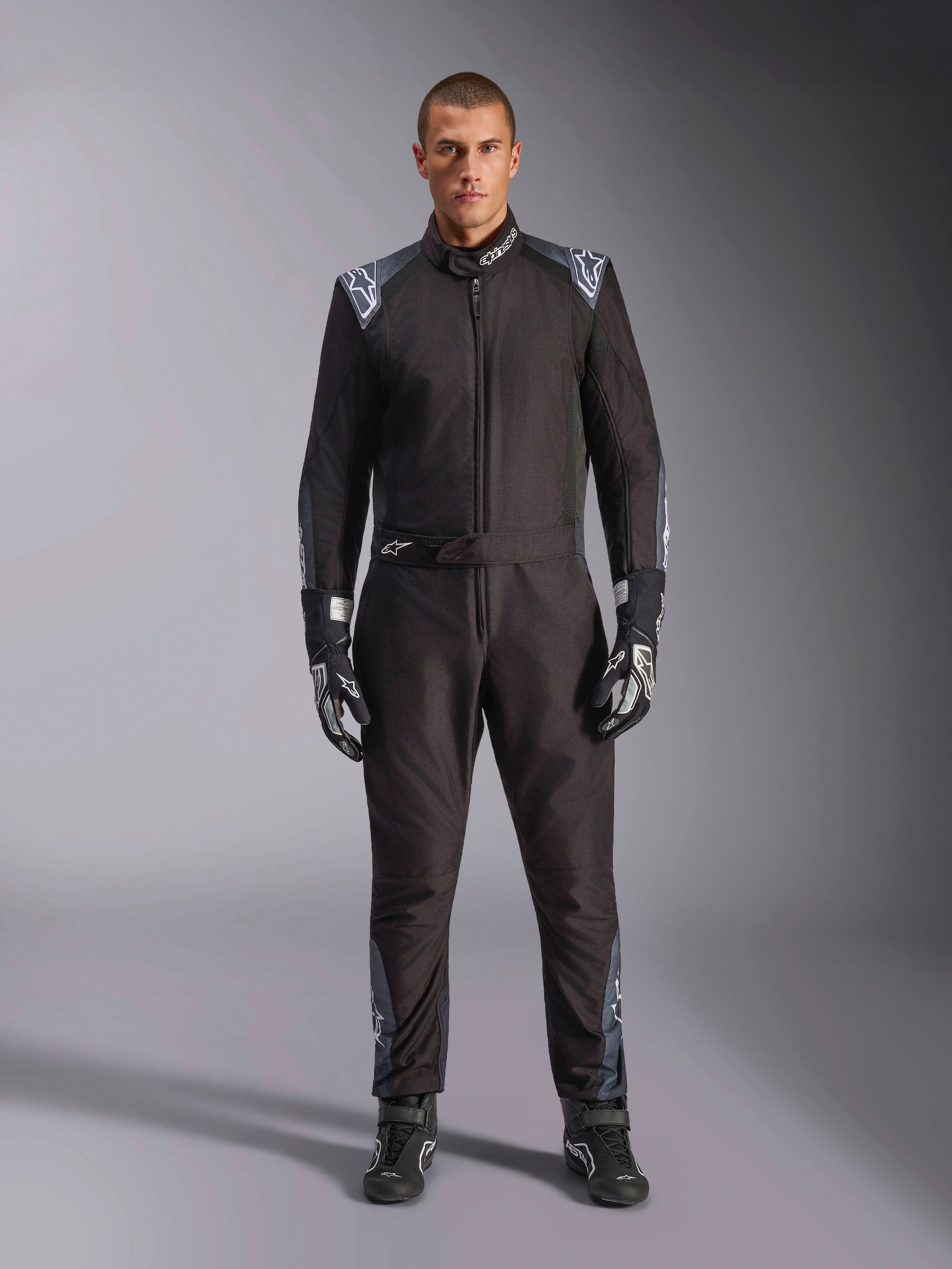 Tuta Alpinestars KMX-5 V3, tuta da karting, Nero Dark Shadow, vista a figura intera di un modello che indossa la tuta con guanti e stivali coordinati, caratterizzata da dettagli grigio scuro e loghi Alpinestars bianchi su spalle e cintura, abbigliamento professionale per sport motoristici.