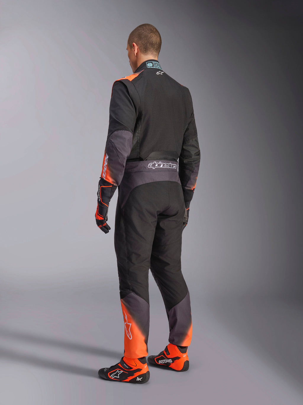 Alpinestars tuta KMX-5 V3 per karting da uomo, vista posteriore, nera e arancione fluo, certificata FIA 8877-2022.