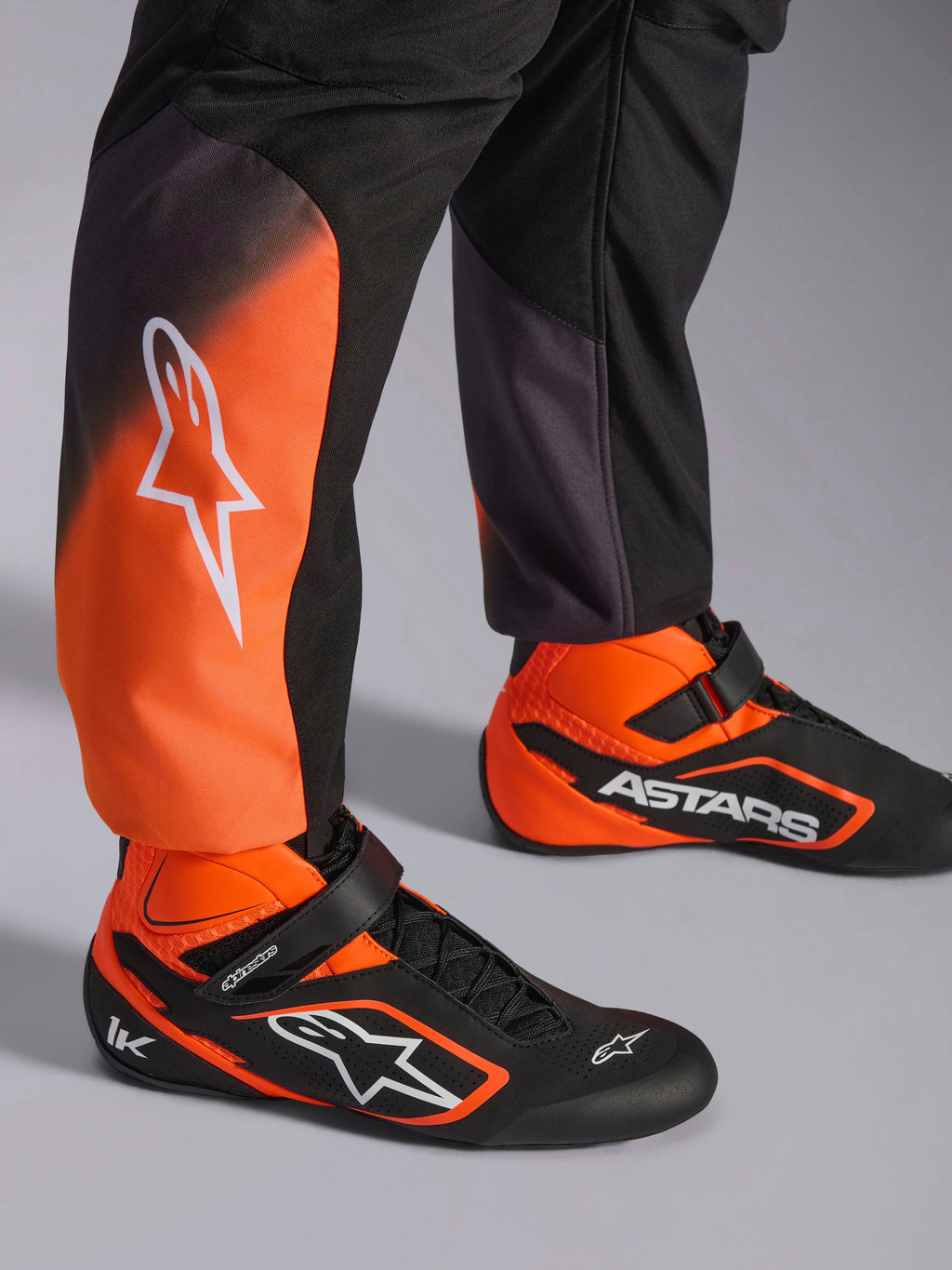 Tuta Alpinestars KMX-5 V3, tuta da karting da uomo, nera e arancione fluo, certificata FIA 8877-2022 Grado 1, dettaglio gambe e scarpe coordinate