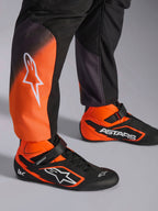 Tuta Alpinestars KMX-5 V3, tuta da karting da uomo, nera e arancione fluo, certificata FIA 8877-2022 Grado 1, dettaglio gambe e scarpe coordinate