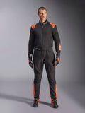Tuta Alpinestars KMX-5 V3 da uomo, nera e arancione fluo, certificata FIA, indossata con guanti e scarpe coordinati.
