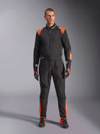 Tuta Alpinestars KMX-5 V3 da uomo, nera e arancione fluo, certificata FIA, indossata con guanti e scarpe coordinati.