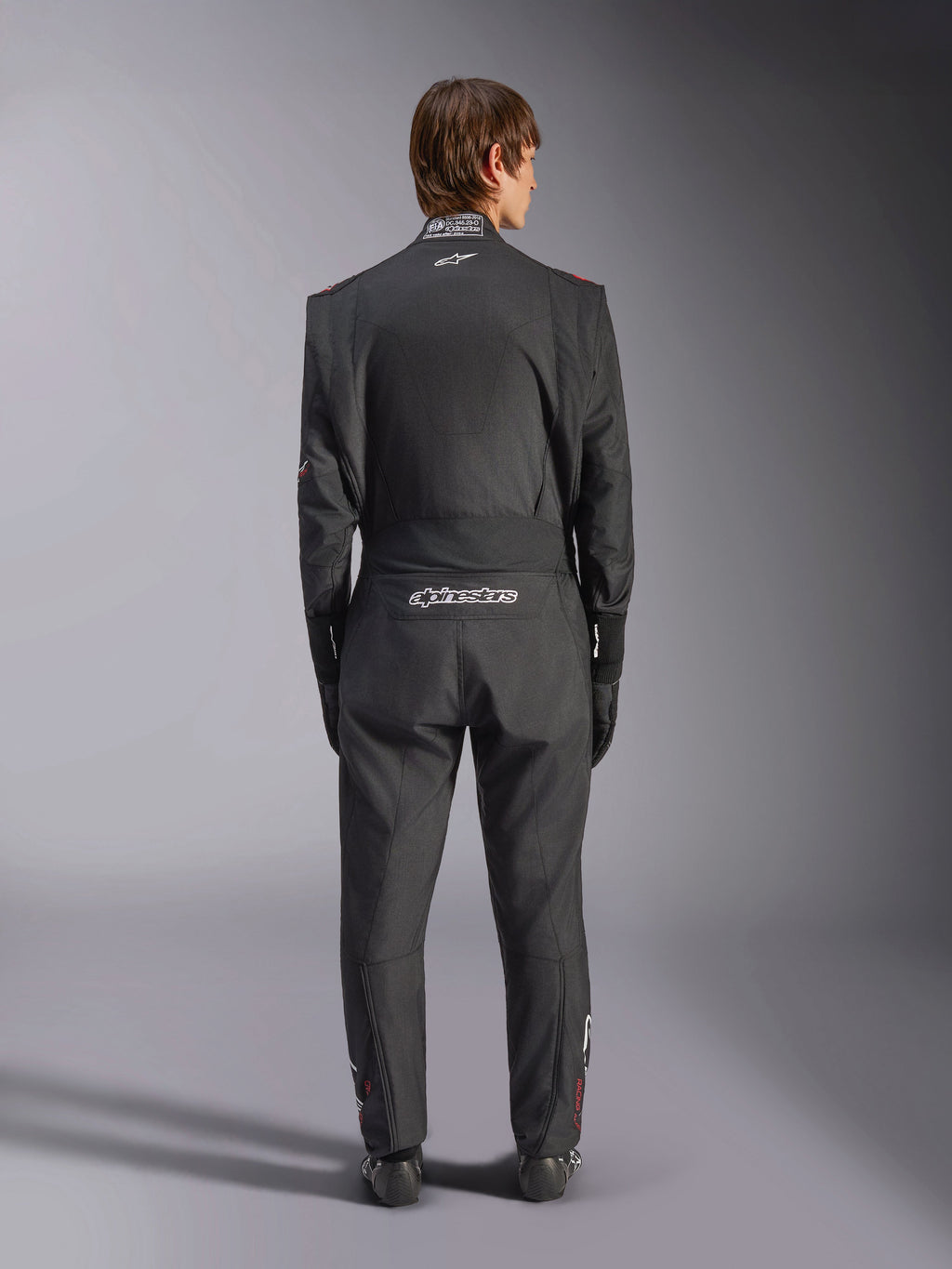 Tuta Alpinestars GP Tech V4, tuta da auto racing, nero e bianco, vista posteriore con logo Alpinestars bianco e certificazione FIA sul colletto, vestibilità ergonomica per la protezione professionale del pilota