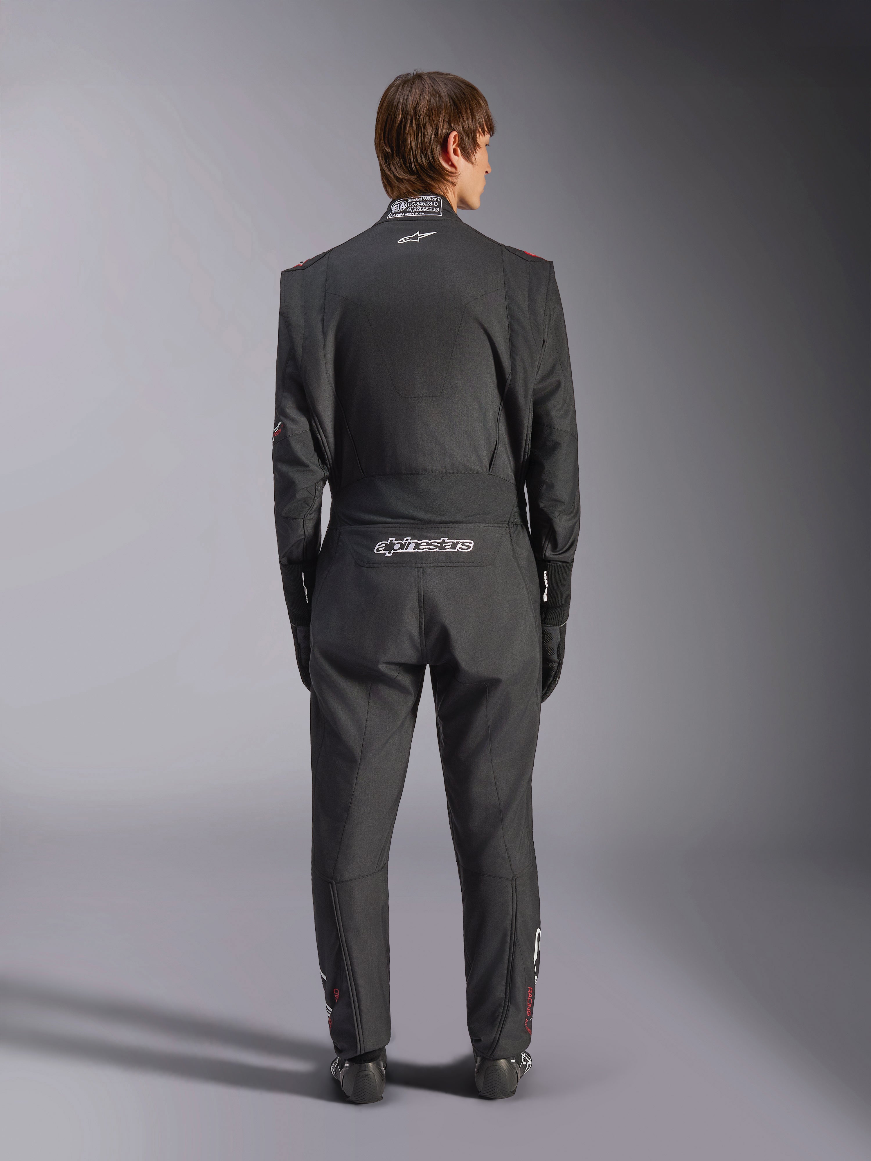 Tuta Alpinestars GP Tech V4, tuta da auto racing, nero e bianco, vista posteriore con logo Alpinestars bianco e certificazione FIA sul colletto, vestibilità ergonomica per la protezione professionale del pilota