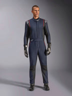Tuta Alpinestars GP Tech V4, tuta professionale da auto racing in blu navy e nero con profili rossi, abbigliamento da corsa intero certificato FIA, indossata con guanti e calzature da corsa neri, abbigliamento per piloti di motorsport