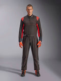 Tuta da Kart Alpinestars KMX-9 V3, nero e rosso fluo, tuta intera da corsa indossata con guanti e stivali coordinati, vivaci inserti rossi sulle spalle e cuciture, logo Alpinestars sulla parte inferiore delle gambe, design motorsport per corse in pista