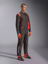 Alpinestars KMX-9 V3 Suit, Karting Suit, Black Red Fluo, worn by a model with orange gloves and black racing shoes, featuring red stitching, shoulder accents, and white logos, athletic design for professional racing