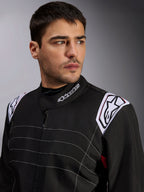 Tuta Alpinestars KMX-9 V3, tuta da kart nera indossata da un modello, primo piano di petto e spalle con logo bianco su colletto e spalline, cuciture decorative bianche e design professionale da motorsport