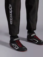Tuta Alpinestars KMX-9 V3, tuta da kart, nero rosso e bianco, vista dettagliata della parte inferiore delle gambe e degli stivali da kart, branding Alpinestars bianco sul lato, scarpe nere con lacci rossi e accenti bianchi, abbigliamento professionale per competizioni motoristiche