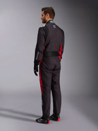 Alpinestars KMX-9 V3 Graphic 3 Suit, nero e rosso, vista posteriore del modello con attrezzatura completa da kart inclusi guanti neri e stivali da corsa, con pannelli laterali rossi e dettagli del logo bianchi