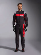 Tuta Alpinestars KMX-9 V3 Graphic 3, tuta da karting, nero e rosso, vista frontale a figura intera indossata da un modello, con pannelli grafici rossi e loghi bianchi, abbinata a guanti e scarpe da corsa neri, abbigliamento professionale per motorsport