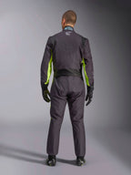 Vista posteriore a figura intera di una persona che indossa la Tuta Alpinestars KMX-9 V3 Graphic 3, tuta da karting in nero e giallo fluo, che mostra i pannelli elastici ergonomici sulla schiena e sulle spalle, abbinata a guanti da corsa e calzature neri.