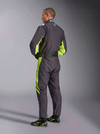 Tuta Alpinestars KMX-9 V3 Graphic 3, tuta da kart, nero e giallo fluo, vista posteriore del modello che mostra il design a pezzo unico con accenti giallo fluorescente sui fianchi e sotto le ascelle, pannelli elastici ergonomici sulla zona lombare e cintura regolabile in vita, indossata con scarpe da gara coordinate.