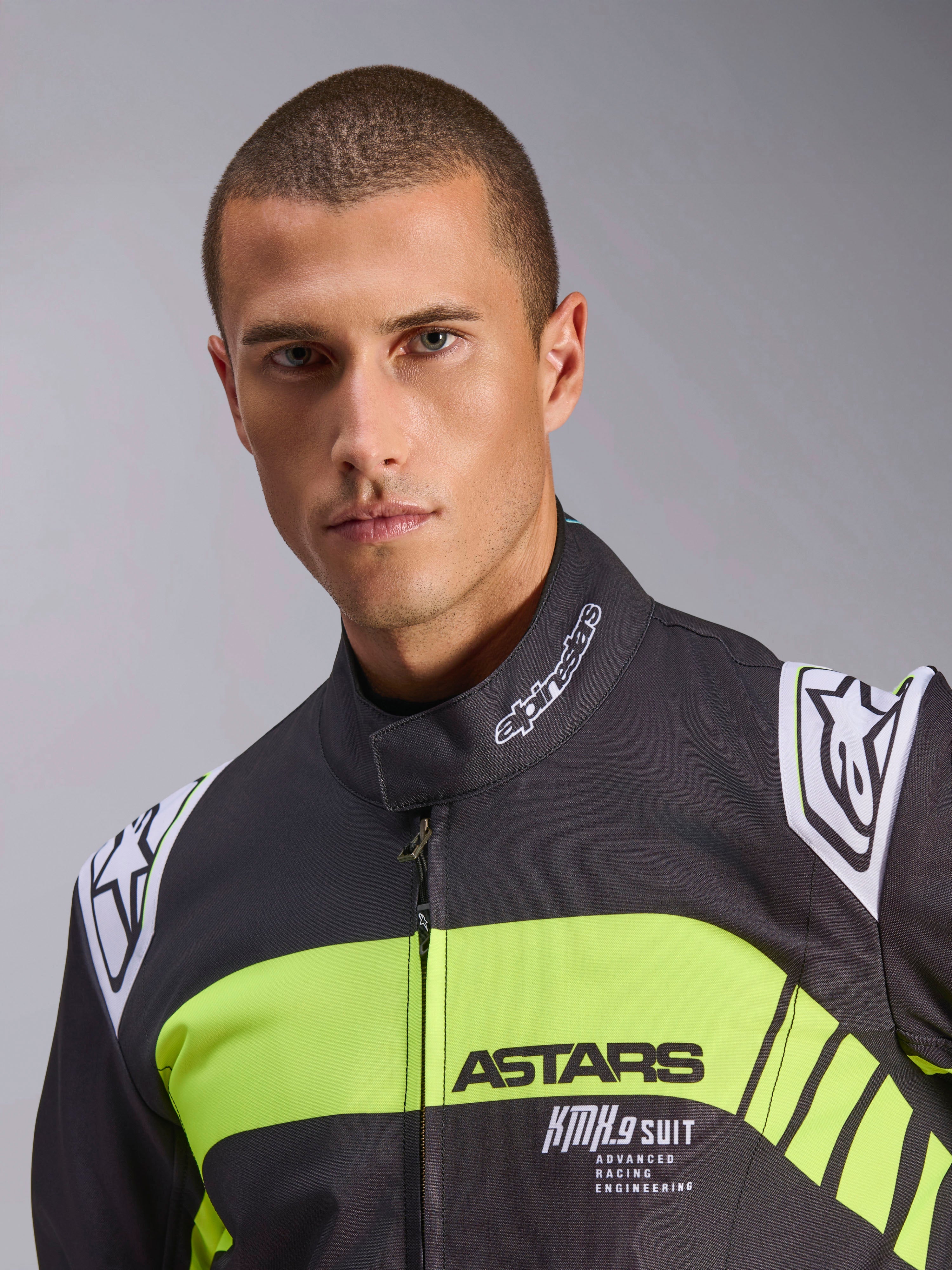 Tuta Alpinestars KMX-9 V3 Graphic 3, tuta da karting, nero e giallo fluo, primo piano con striscia gialla fluorescente sul petto e marchi ASTARS e KMX.9 SUIT, loghi Alpinestars su spalle e colletto, abbigliamento professionale da gara