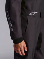 Dettaglio ravvicinato della tuta Alpinestars KMX-9 V3 Graphic 3 in nero, che mette in risalto la cintura regolabile con logo bianco, il marchio verticale sulla manica e i polsini in maglia.
